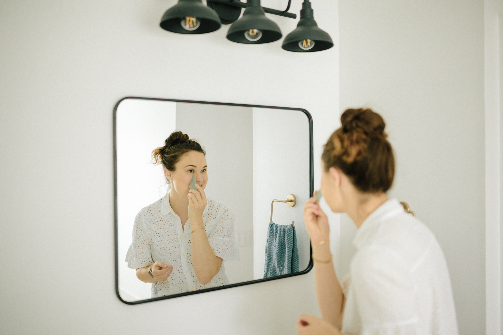 Carolina showing the benefits of gua sha techniques in the mirror.